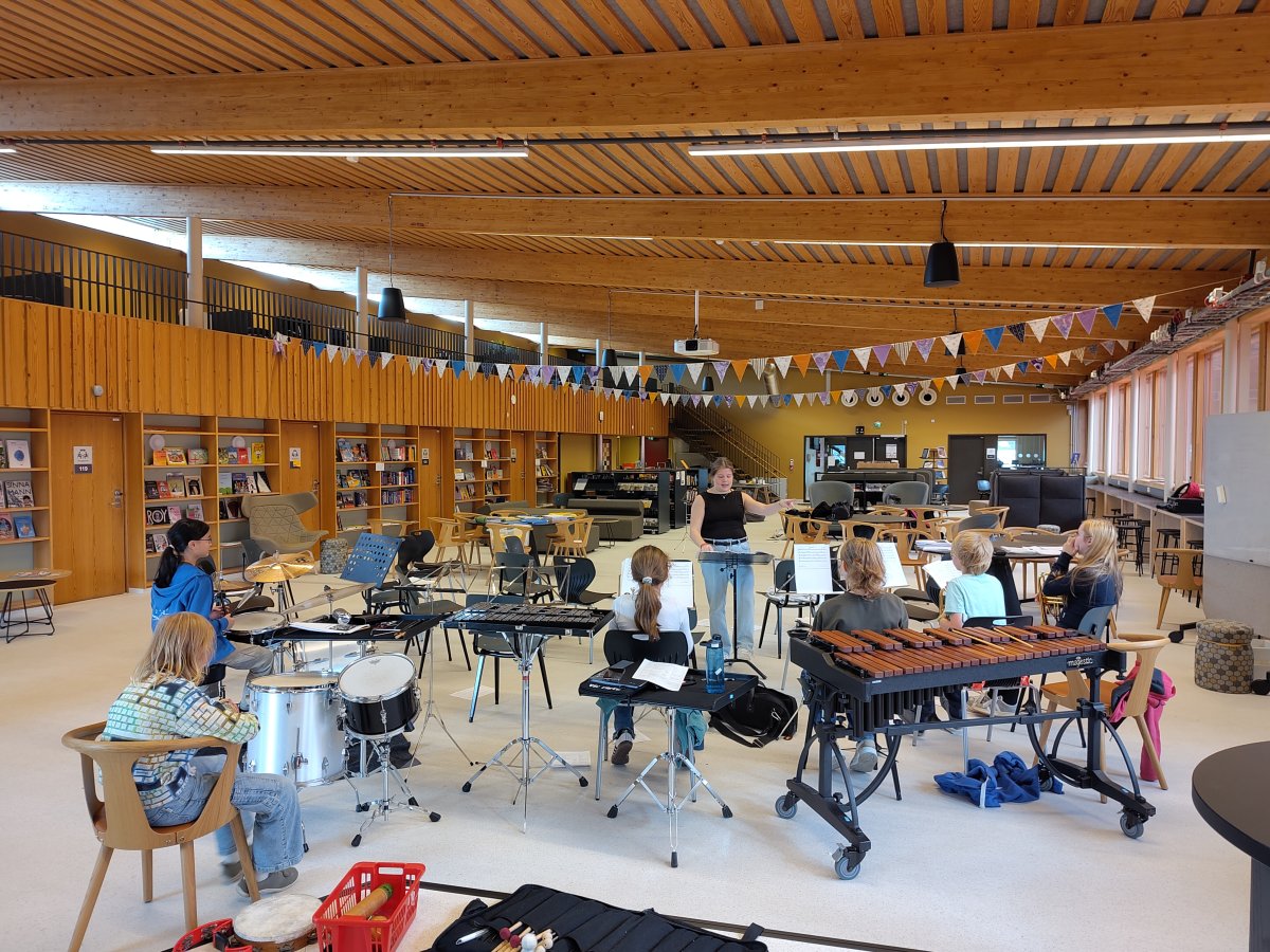 Gruppeøving hovedkorps med kornett og slagverk, dirigent vendt mot kamera, musikantane bakfrå.