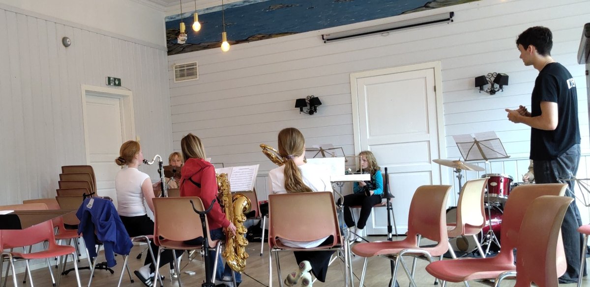 Bilete av musikantar på slagverk, bassklarinett, barytonsaksofon og trombone. Dei tre siste sit med ryggen til.
